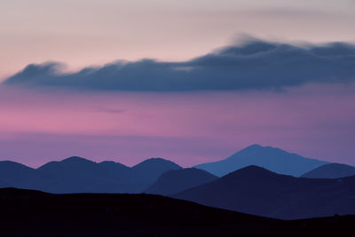 Scenic view of silhouette mountains against romantic sky