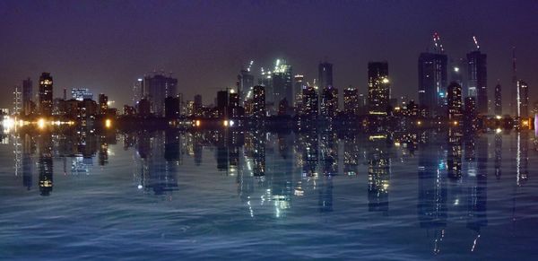 Illuminated buildings by swimming pool at night