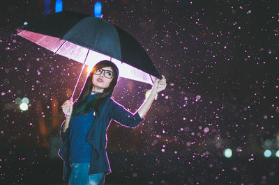 Beautiful young woman holding umbrella during winter