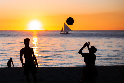 Silhouette people at beach during sunset