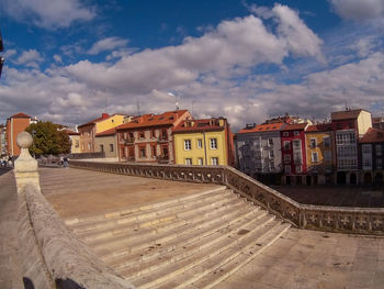 Footpath by buildings in city against sky