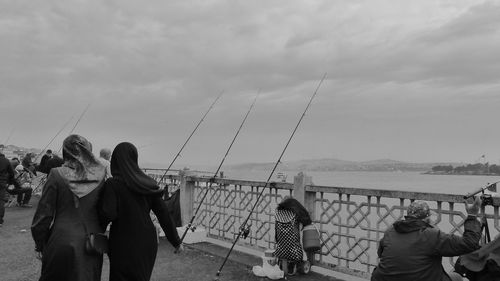 Rear view of women wearing hijabs walking by lake against sky