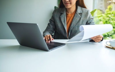 Midsection of businesswoman using laptop at office