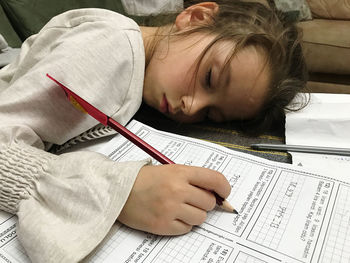 High angle view of girl sleeping while studying