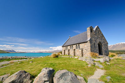 Old building by sea against blue sky