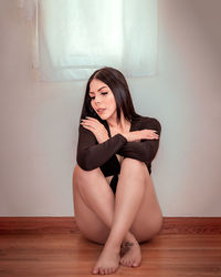 Portrait of young woman sitting on hardwood floor at home