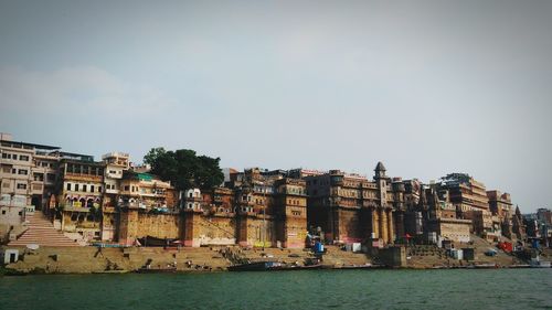 Buildings by sea against clear sky