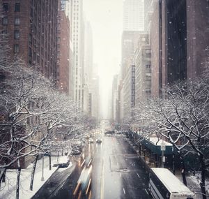 Road amidst buildings in city during winter