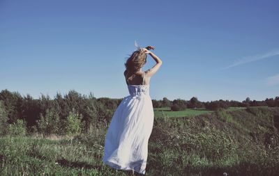 Rear view of young woman standing on field