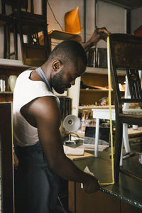 Male entrepreneur measuring wooden chair at workshop