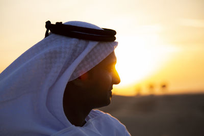 Close-up of man in traditional clothing against sky during sunset