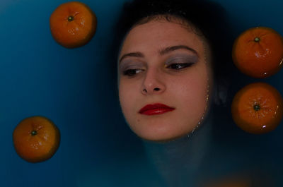 Woman with orange fruits in bathtub