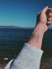 Low section of person against sea against clear sky