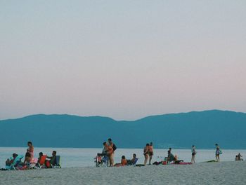 Group of people on beach against clear sky