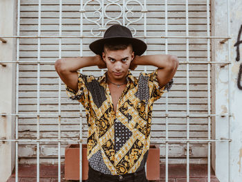 Portrait of young man standing against wall