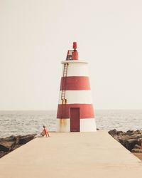 Lighthouse by sea against clear sky