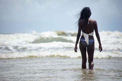 Rear view of young woman standing at beach