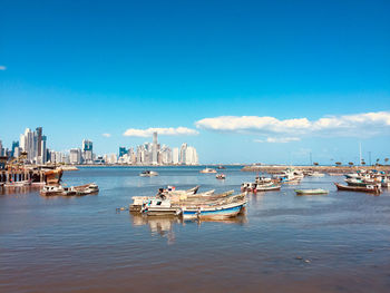 Boats moored in sea against blue sky