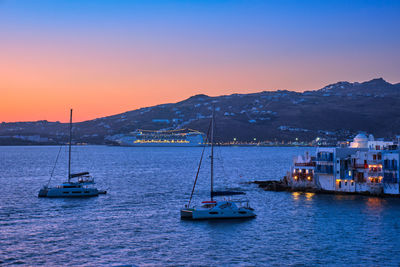 Sailboats in sea against sky during sunset