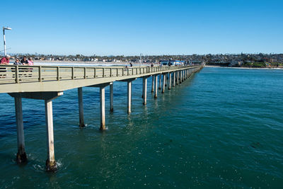 Pier over sea against clear blue sky