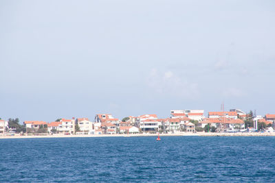 Sea by buildings against sky in city