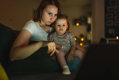 Portrait of cute girl sitting on sofa at home