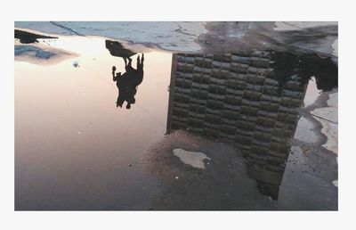 Reflection of people on puddle in city