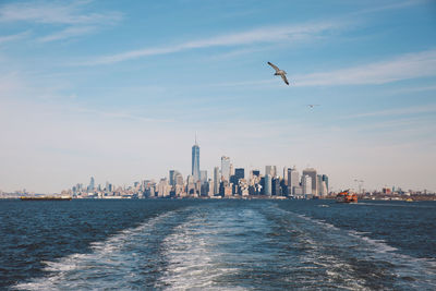 Sea by cityscape against sky