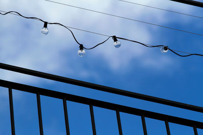 String of unlit light bulbs silhouetted against the blue sky.