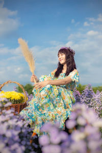 Woman standing by flowering plants against sky