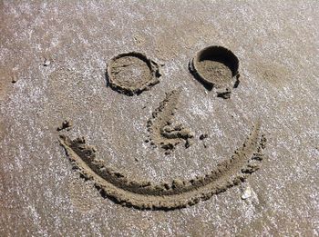 High angle view of anthropomorphic smiley face drawn on sand at beach