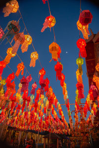Low angle view of illuminated lanterns hanging by building against sky