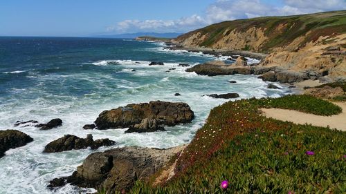 Scenic view from cliffs of sea against blue cloudy hazy sky