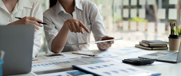 Midsection of business people working on table