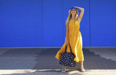 Full length of woman standing against blue wall