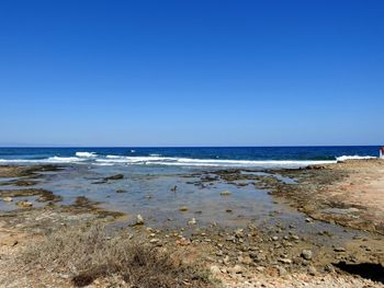 View of calm beach against clear blue sky