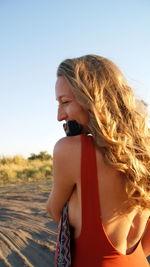 Beautiful young woman standing against clear sky