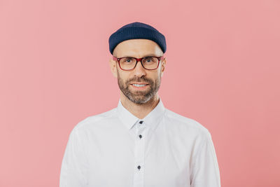 Portrait of young man standing against red background