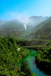 Scenic view of river by mountains against sky