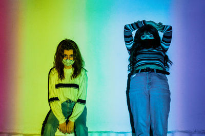 Portrait of woman wearing mask standing against wall