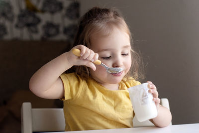 Cute girl eating yogurt at home