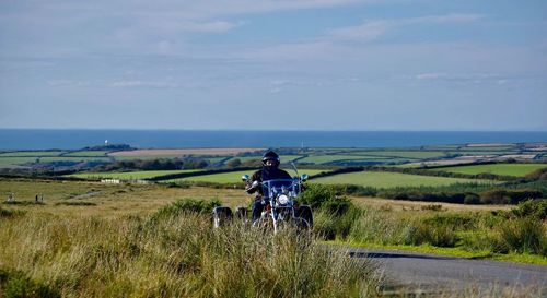 Man riding motorcycle on field against sky
