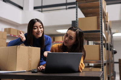 Portrait of young woman using laptop while sitting in office