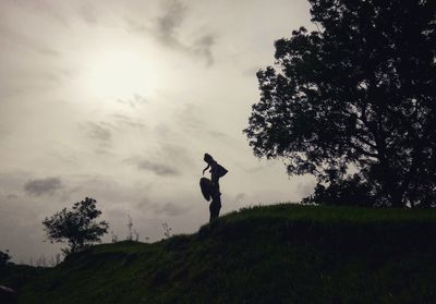 Silhouette woman playing with daughter while standing on land against sky