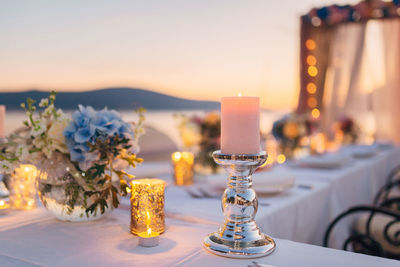 Close-up of illuminated place setting at restaurant against sky during sunset