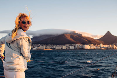 Portrait of woman standing in boat on sea against sky