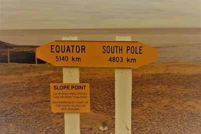 Information sign on beach against sky
