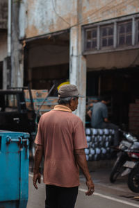 Rear view of man walking on street in city