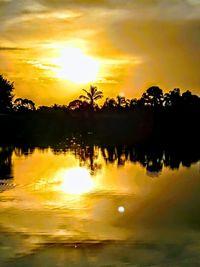 Silhouette trees by lake against sky during sunset