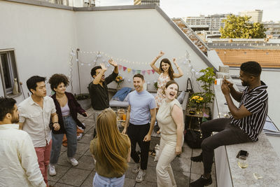 Man photographing group of friends dancing in party in balcony